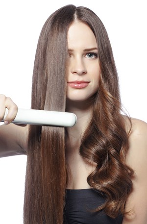 Beautiful girl using hair styler for straight hair and curls