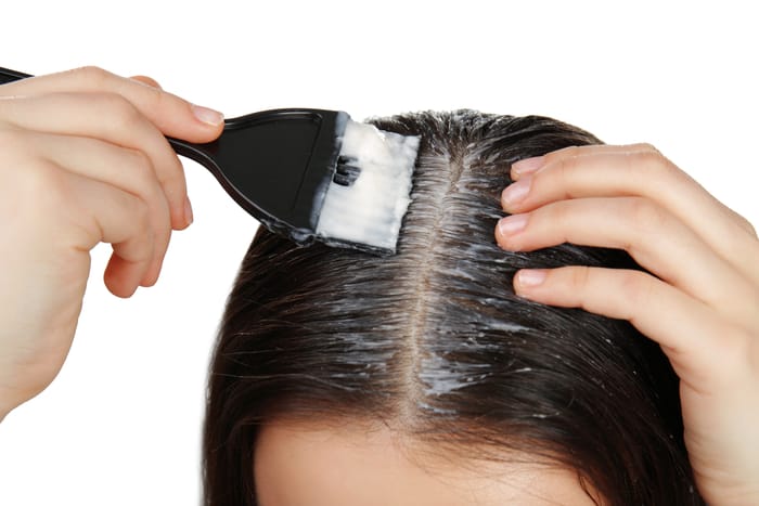 Young woman applying coconut oil onto scalp